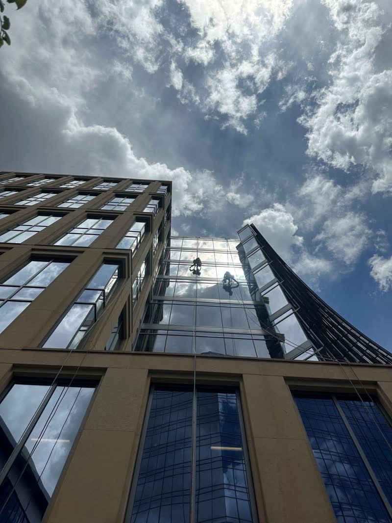 Two S&K rope technicians on the glass section of a stone-clad office building in Denver