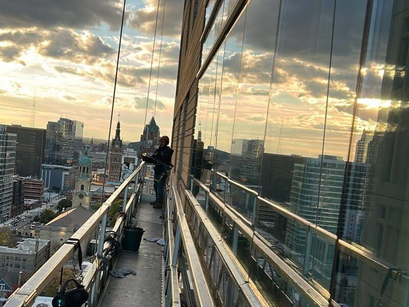 Swing stage at dusk on a Milwaukee tower with City Hall behind