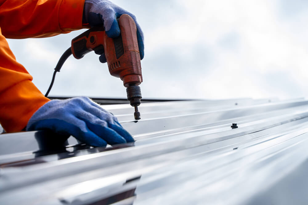 Roofer worker using air or pneumatic nail gun and installing metal